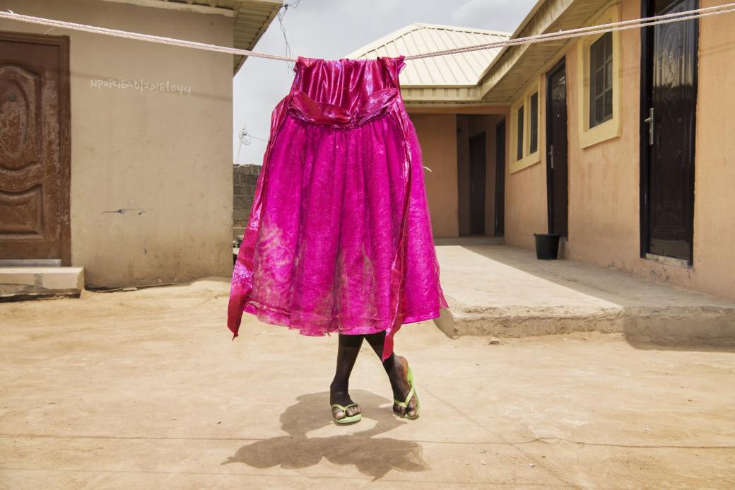Tại trại trẻ mồ côi ở Gwagwalada, Nigeria, một cô bé đang đứng nghỉ phía sau một bộ váy đang phơi, là sự biểu trưng của một đứa trẻ đã chết. Theo văn hóa truyền thống, nếu người anh chị em của một cặp sinh đôi đã chết, thì đứa trẻ còn lại không nên và phải hạn chế nhắc đến nửa kia của mình.