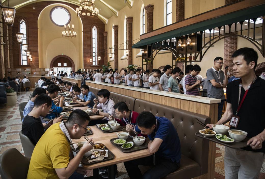Nhân viên Huawei đang xếp hàng chờ lấy thức ăn, trong khi những người khác đang ngồi dùng bữa, trong khu vực nhà ăn được thiết kế hệt những cung điện ở Châu Âu.