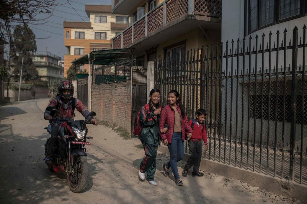 Unika đi bộ đến trường cùng hai người em của mình. Trước đây khi còn là nữ thần sống, cô bé được đông đảo người vây xung quanh, họ đến từ khắp đất nước Nepal để cầu xin, khấn vái. Giờ đây, cô bé chỉ nhận được sự chú ý từ gia đình và bạn bè trong lớp học.