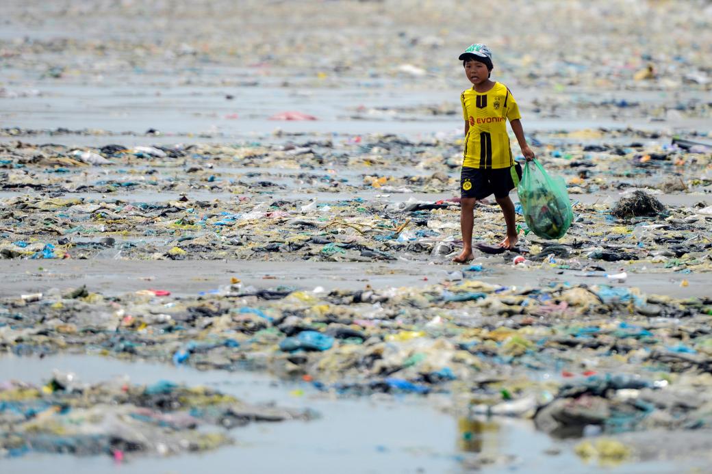 Một cậu bé bước trên bờ biển tại cửa sông Thu Bồn (Hội An, Quảng Nam) được phủ kín bởi rác thải nhựa.