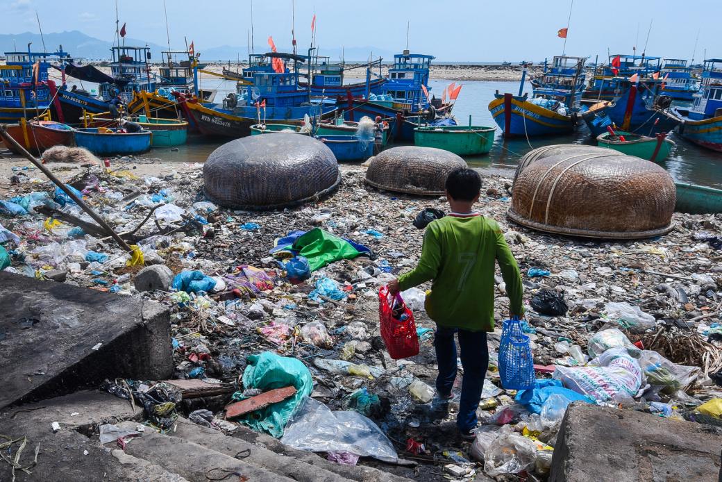 Một chú nhóc vượt qua bãi biển đầy rác để mang đồ lên thuyền ở thị trấn Liên Hương, huyện Tuy Phong (Bình Thuận). Buổi tối ở đây có những chú chuột cống to kinh hoàng, chúng kiếm ăn quanh đống rác khiến người cũng phải sợ.