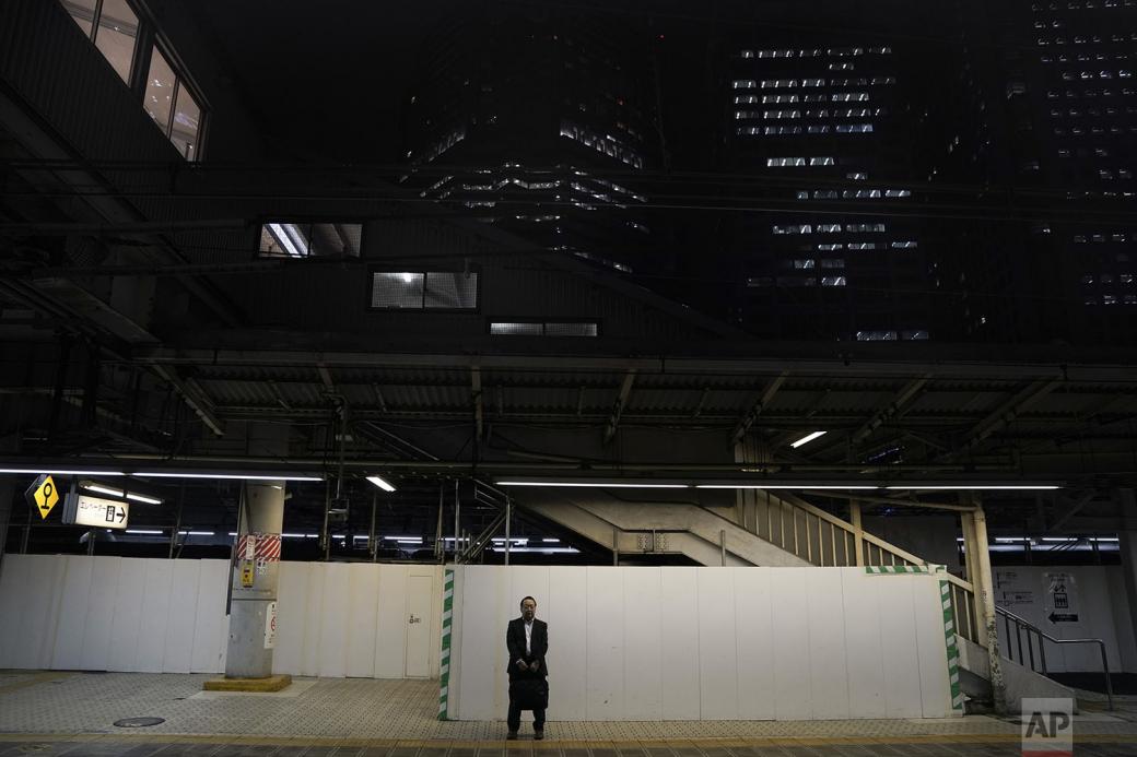 Người đàn ông đứng một mình giữa không gian rộng, vắng vẻ và yên tĩnh để chờ chuyến tàu tiếp theo.