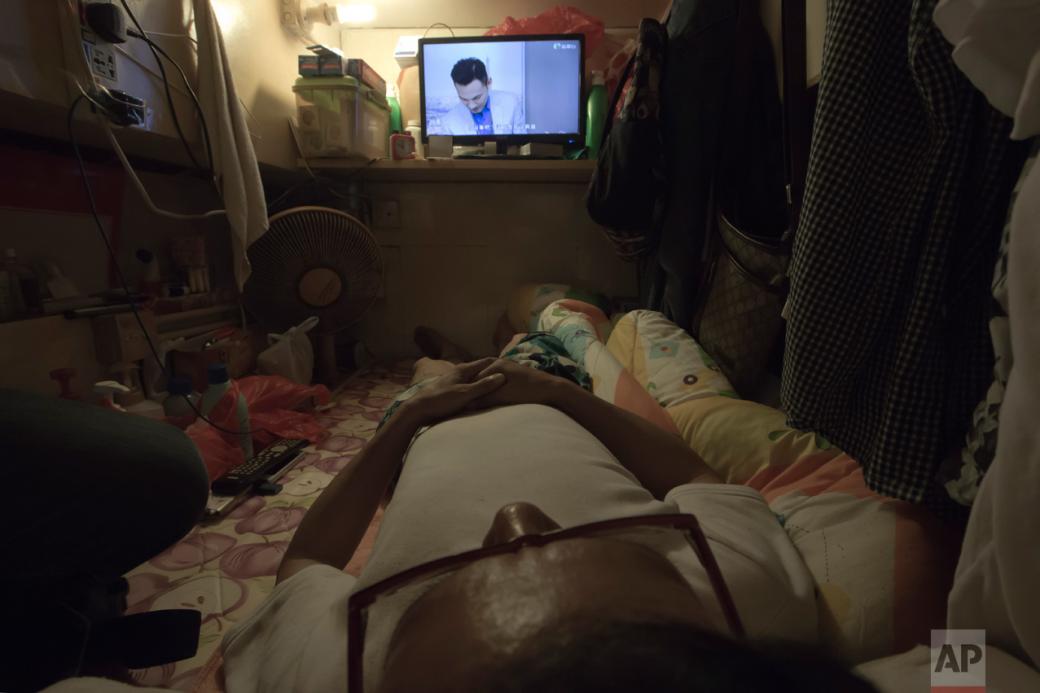 Ông Wong nằm xem TV trên chiếc giường và bên cạnh những nhu yếu phẩm, đó là tất cả những gì ông có và chúng được gói gém tài tình trong một không gian chật hẹp.