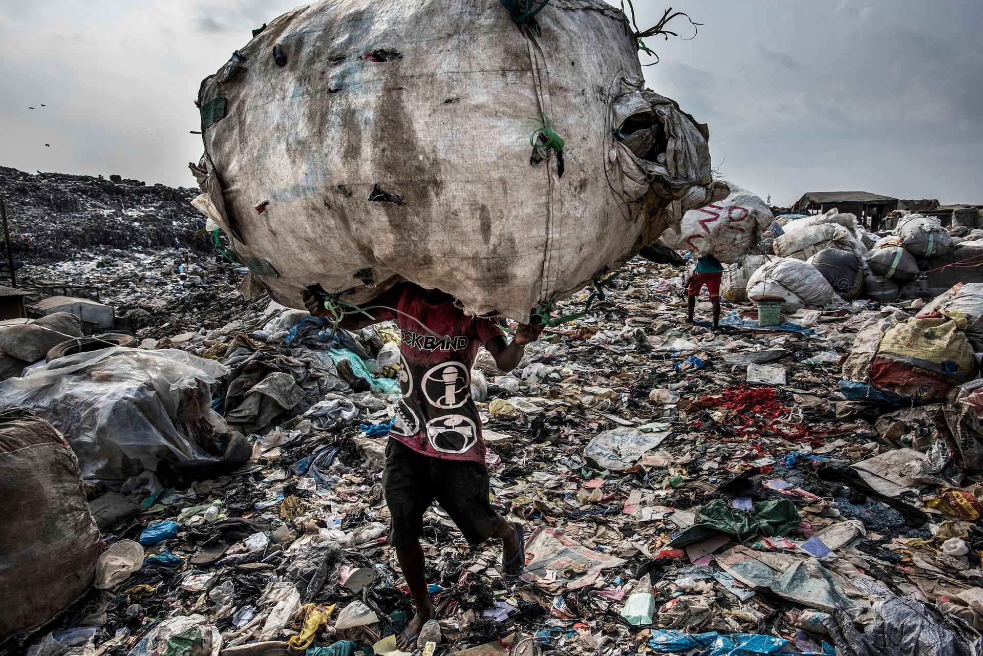 Giải nhất hạng mục Môi trường. Một người đàn ông đang đội trên đầu một túi rác khổng lồ chứa chai nhựa và mang đi tái chế, ảnh chụp tại bãi rác Olusosun ở Lagos, Nigeria. Ảnh: Kadir Van Lohuizen/Noor Images/Handout/EPA.