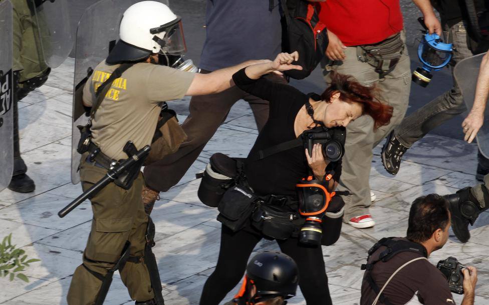 a riot policeman punches greek photojournalist