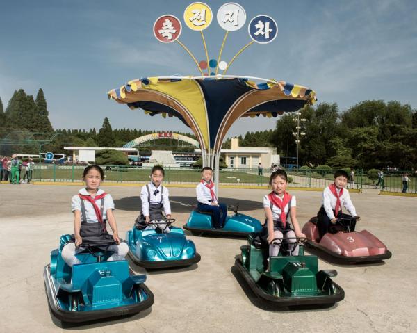 Những em nhi đồng tạm ngừng trò chơi của mình trên những chiếc xe điện đụng ở Hội chợ giải trí Mangyongdae, ngoại ô Bình Nhưỡng. Ở quốc gia khép kín này, rất ít người có kinh nghiệm tạo dáng trước ống kính.