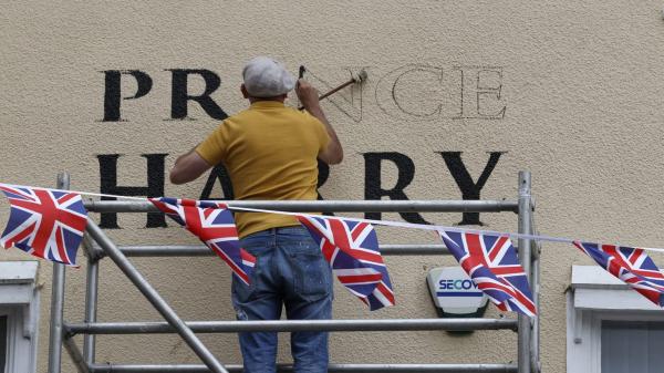 Một người thợ đang sơn những chữ cái cuối cho cụm từ “Prince Harry” ở bên ngoài một quán rượu gần Lâu đài Windsor. Ảnh: AFP/Getty Images.