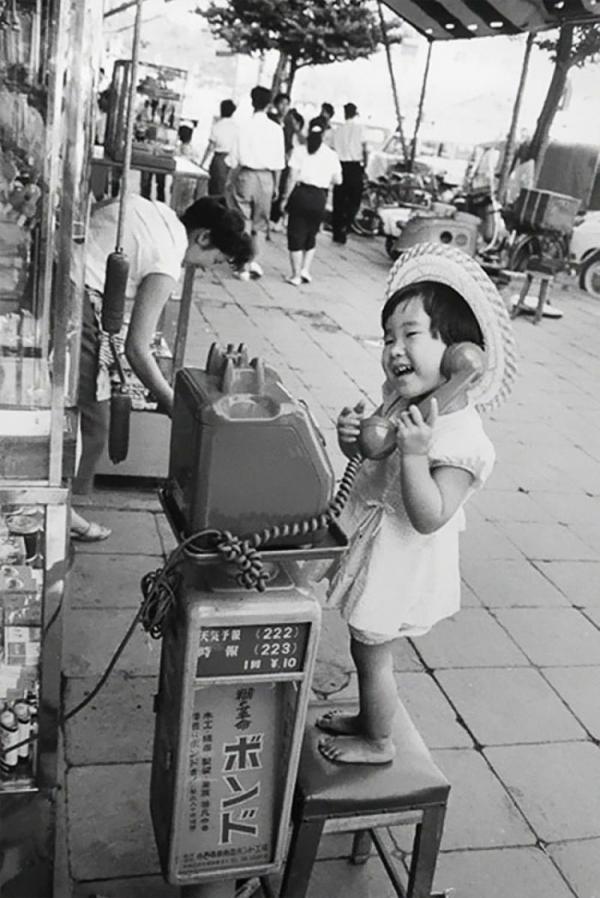 a little girl having fun pretending to talk on the telephone japan 1958