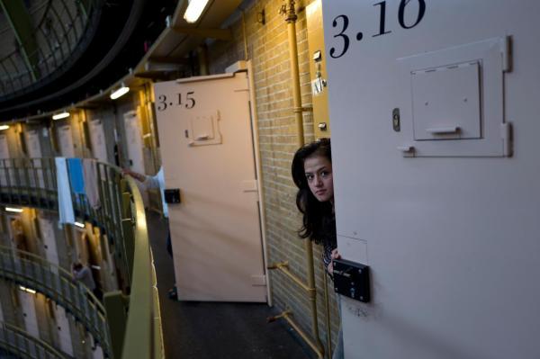 Một người tị nạn Afghanistan 19 tuổi đang liếc nhìn qua cửa phòng của cô tại nhà tù De Koepel ở Haarlem, Hà Lan.