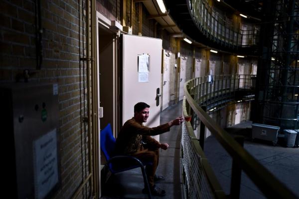 Siratullah Hayatullah năm nay 23 tuổi, là người tị nạn Afghanistan, đang uống trà bên ngoài cửa ra vào của phòng mình, nhìn ra sân chung ở nhà tù De Koepel.