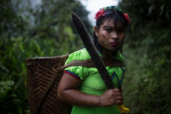 Cầm trên tay một con dao và khoác lên người chiếc giỏ đựng thức ăn, một phụ nữ người Emberá Katío đang nhìn chằm chằm vào người chụp ảnh. Dân làng La Puria vẫn giữ truyền thống từ nhiều đời trước để sinh tồn, họ săn bắt và trồng trọt với quy mô nhỏ.