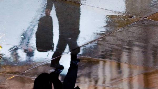 reflection of a business man walking in the rain with an umbrella