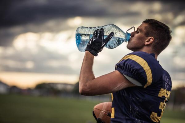 thirsty football player drinking water from a large bottle
