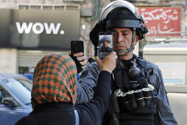 Một phụ nữ người Palestine quay hình phát trực tiếp thành viên của lực lượng an ninh Israel khi ông đang chụp ảnh của chính mình bằng điện thoại của ông, trên một con phố ở Jerusalem vào 16/12/2017. Lúc bấy giờ các cuộc biểu tình vẫn đang bùng phát liên tục ở Trung Đông và nhiều nơi khác ở Jerusalem sau tuyên bố của Tổng thống Trump cho rằng thành phố này là thủ đô của Israel. Ảnh: Ahmad Gharabli/AFP/Getty.