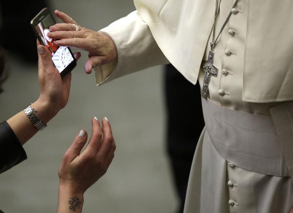 Đức Giáo Hoàng Francis đang ban phước lành cho một đứa trẻ lên bức ảnh của đứa bé đó trong điện thoại di động của người mẹ. Hình ảnh này được chụp trong khuôn khổ một buổi nói chuyện của Đức Giáo Hoàng với công chúng tại Quảng trường Thánh Paul VI ở Vatican vào 16/01/2016. Ảnh: Alessandra Tarantino/AP.