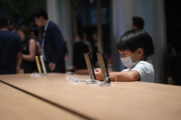 Một cậu bé đang sử dụng điện thoại iPhone tại cửa hàng Apple đầu tiên ở Thái Lan bên trong IconSiam, khu phức hợp mua sắm và nhà ở cao cấp trị giá 54 tỷ Baht (1,65 tỷ USD) bên bờ sông Chao Praya, thủ đô Bangkok. Ảnh: Lillian Suwanrumpha/AFP/Getty.