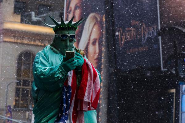 Mặc cho tuyết đang rơi nhiều, một người mặc trang phục hóa trang đang sử dụng điện thoại và đợi khách vãng lai đến để chụp ảnh cùng mình, tại Quảng trường Thời Đại, New York. Ảnh: Eduardo Munoz Alvarez/AFP/Getty.