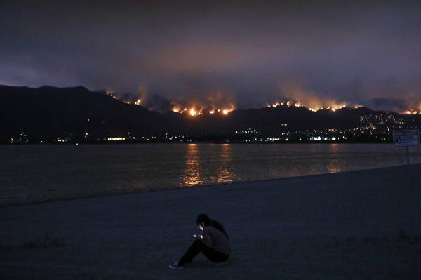 Một cô gái trẻ đang sử dụng điện thoại trong khi ở đằng xa là đám cháy lớn thiêu rụi Rừng quốc gia Cleveland ở Elsinore, California vào tháng 8 vừa qua. Ảnh: Mario Tama/Getty.