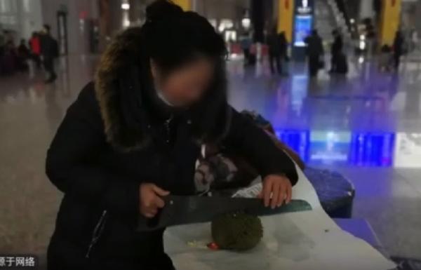 a woman eat a durian at railway station