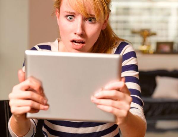 2 young woman looking at tablet computer in shock and horror