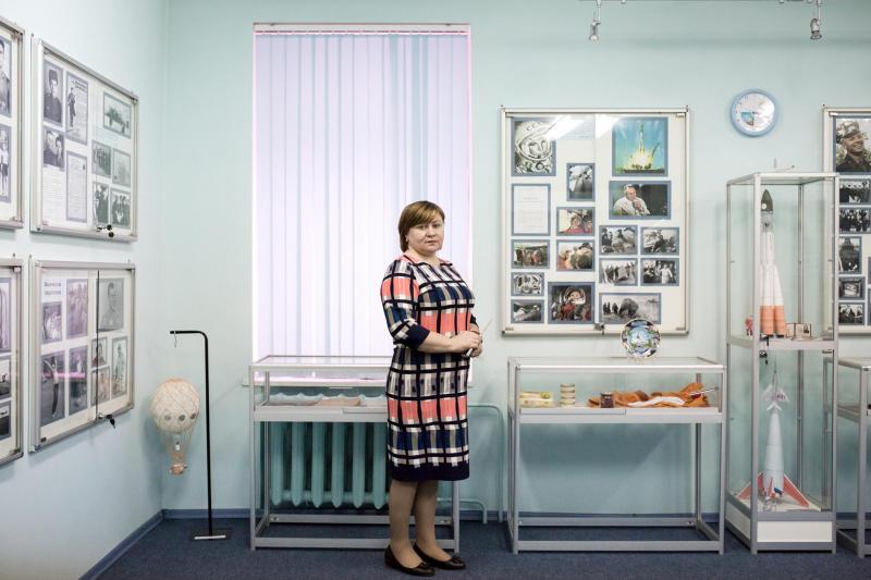 Natalia Tabac, giáo viên hiệu trưởng của một trường học tại làng Gagarin, đang đứng bên cạnh tủ đựng những đồ vật mô phỏng chuyến bay đầu tiên của Gagarin được dùng cho việc giảng dạy.
