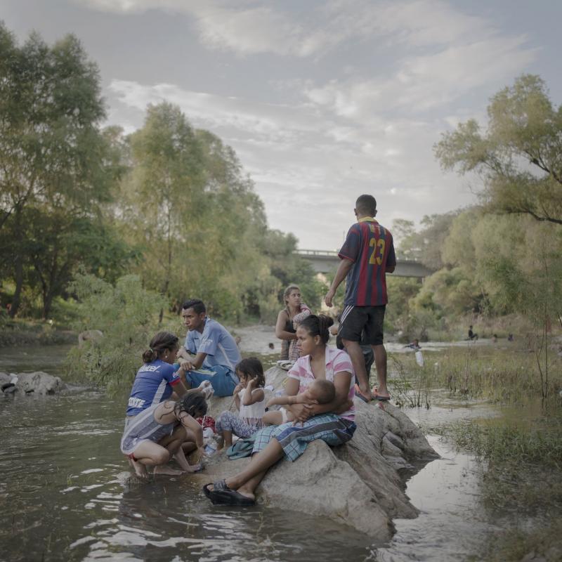 Sau gần một tuần đi bộ miệt mài, đoàn người di cư có một ngày nghỉ trước khi bắt đầu lao vào cuộc bộ hành mịt mờ tương lai. Trong hình là một gia đình đang tắm rửa, giặt quần áo và thư giãn tại Rio Novillero, gần Tapanatepec, Mexico.