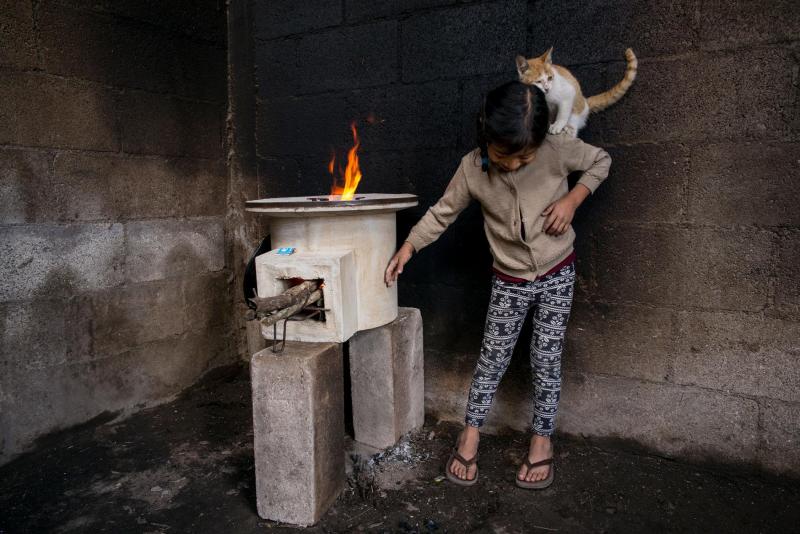 Cô bé Tania López (7 tuổi) đang chơi cùng chú mèo của mình trong căn bếp tại nhà của cô bé ở Guatemala. Bức tường xung quanh đã bị ố đi bởi bếp lò cũ sử dụng than và củi, nhưng đó đã là quá khứ vì bây giờ nhà của cô bé và những hộ dân khác trong vùng đã được sử dụng loại bếp mới rất an toàn, sử dụng nhiên liệu sạch. Ảnh: Lynn Johnson.