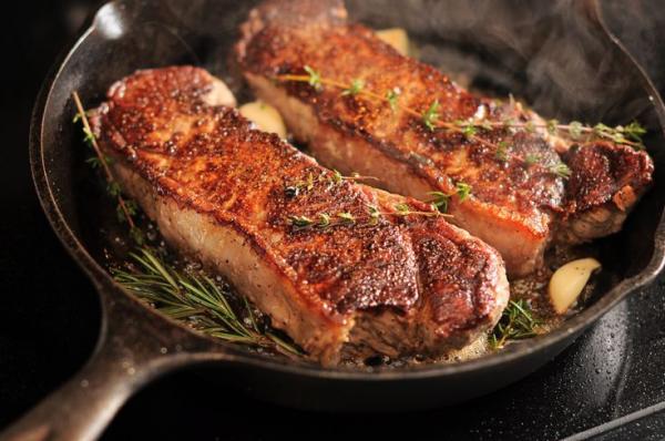 strip loin new york steaks in a cast iron pan 184991653 5a67601eb1f09f0037c53aef