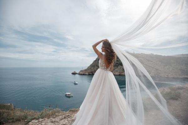 0 beautiful bride in white dress posing on sea and mountains in background